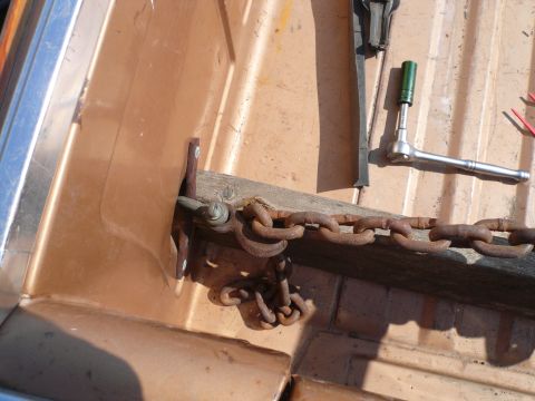 1975 Ford Ranchero - A rusty chain is secured in the bed of a brown truck, with tools nearby.