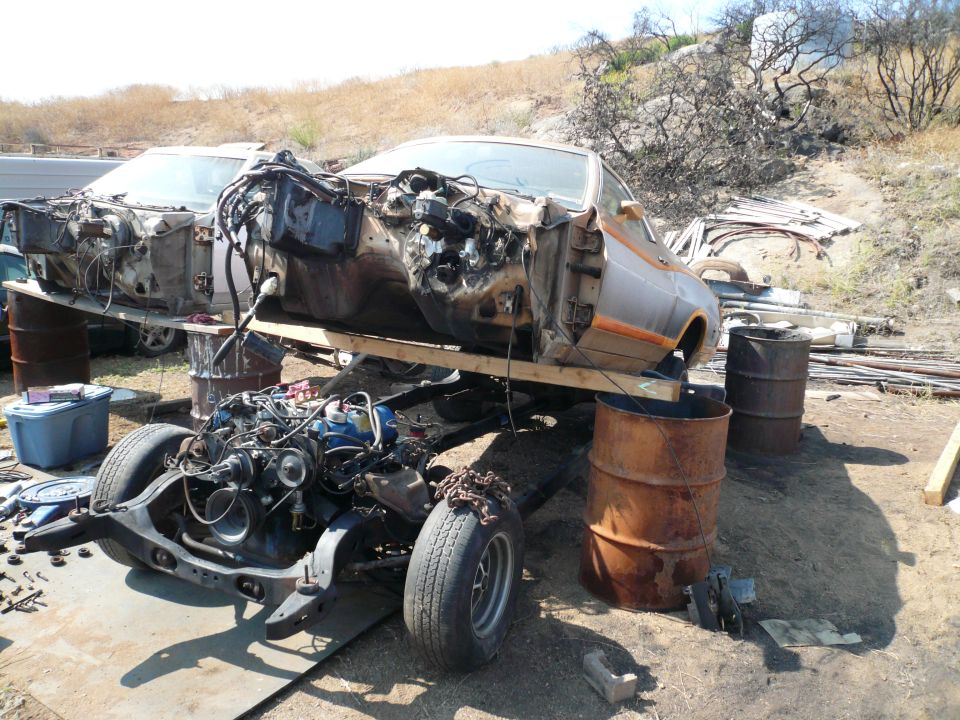 Disassembled 1975 Ford Ranchero body and chassis on barrels