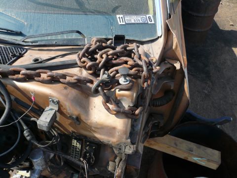 1975 Ford Ranchero - Heavy chains cover the engine bay of a vehicle, with a sticker on the windshield.