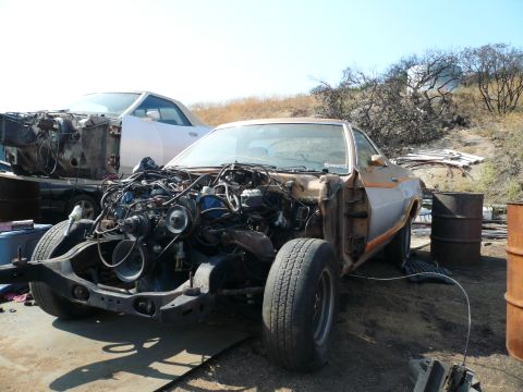 1975 Ford Ranchero - This vehicle is missing its engine and front end components, with another car visible in the background.
