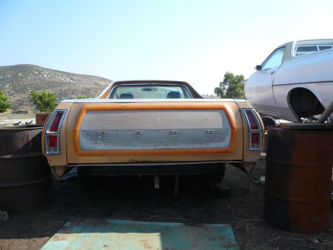 1975 Ford Ranchero - The rear of a 1975 Ford Ranchero shows its distinctive woodgrain trim and 'FORD' badging, with another vehicle visible in the background.