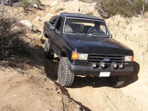 1990 Ford Bronco - This 1990 Ford Bronco navigates a challenging off-road trail with its tires angled on the loose dirt.