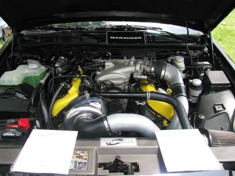 2003 Mercury Marauder - The engine bay of a 2003 Mercury Marauder is shown with a prominent supercharger and custom yellow engine components.