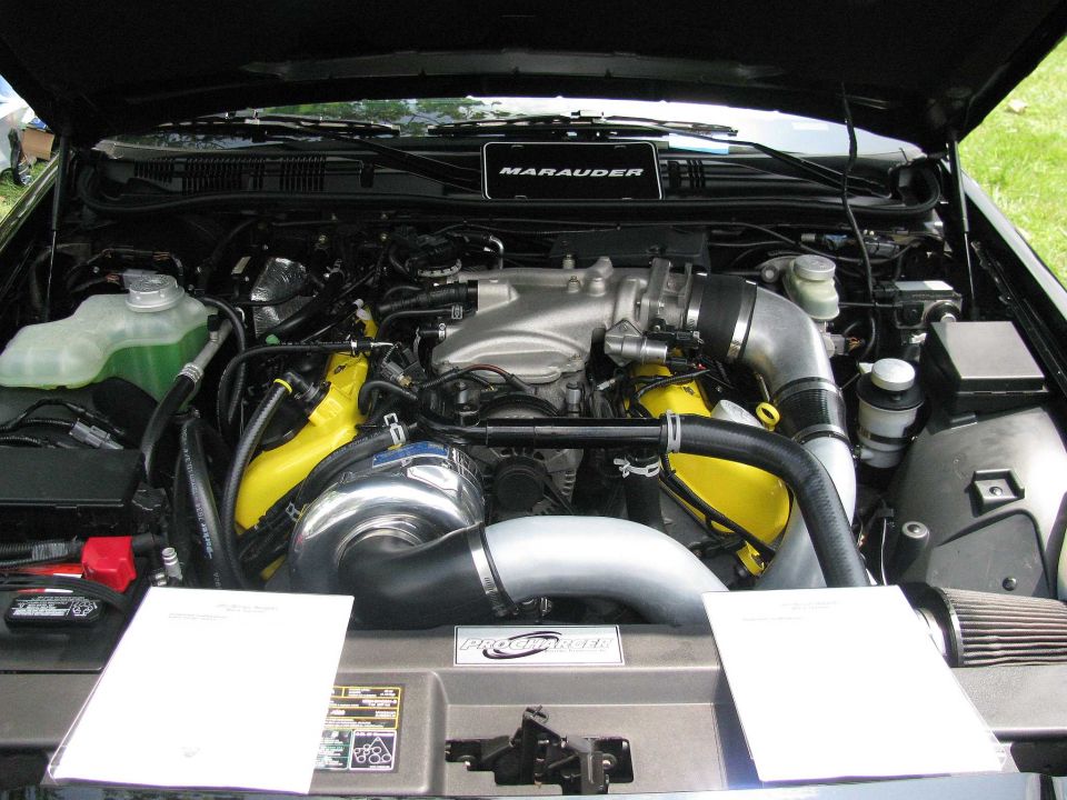 Engine bay of a 2003 Mercury Marauder with a supercharger and yellow accents