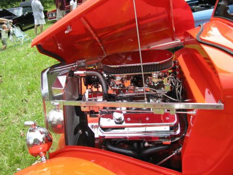 2003 Mercury Marauder - Close-up of a polished chrome engine in an orange hot rod at a car show.