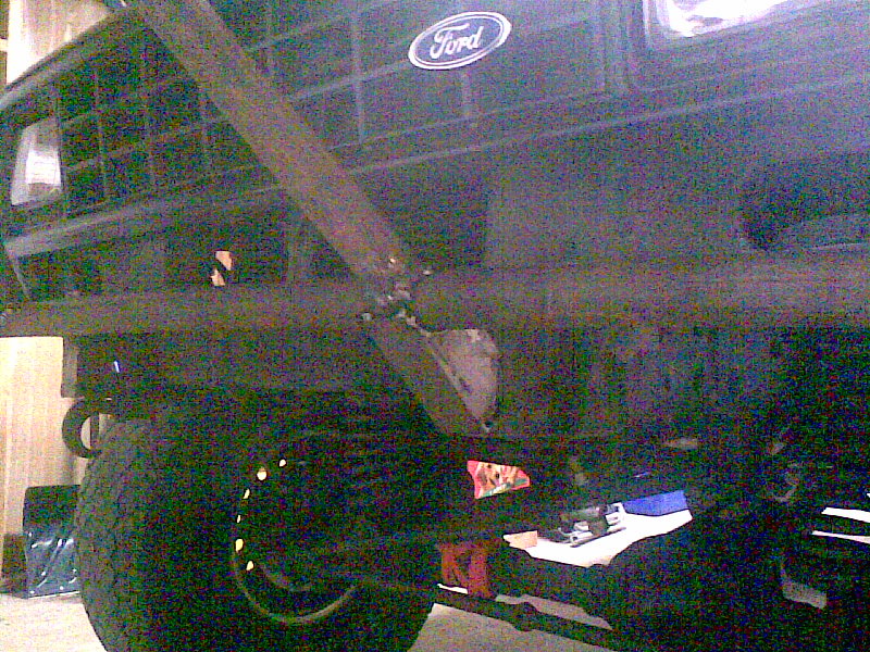 Ford emblem on a dark grille, with a metal bar attached to the front. Shows part of a tire and suspension