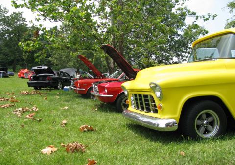 2003 Mercury Marauder - A bright yellow 1955 Chevrolet pickup truck is parked on the grass at a car show, with other vehicles visible in the background.