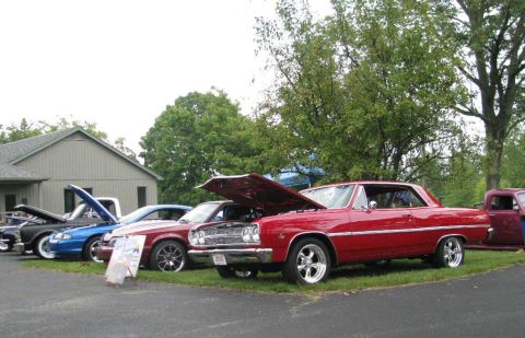 2003 Mercury Marauder - Several cars are parked on grass in front of a building, with trees in the background.