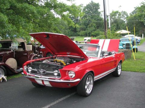 2003 Mercury Marauder - A red 1967 Ford Mustang convertible with its hood open is displayed at a car show, with other vehicles in the background.