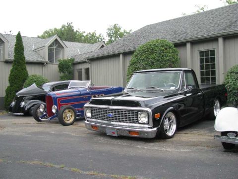 2003 Mercury Marauder - A black pickup truck is parked alongside other custom vehicles in front of a building.