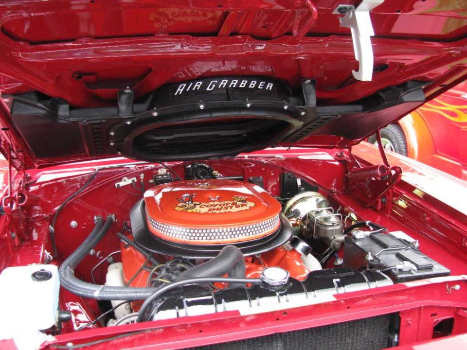 Red classic car engine bay with orange Coyote 5.0 air cleaner and black AIR GRABBER scoop.