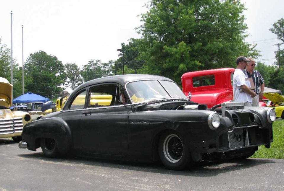 Black custom sedan with exposed engine and modified front end.