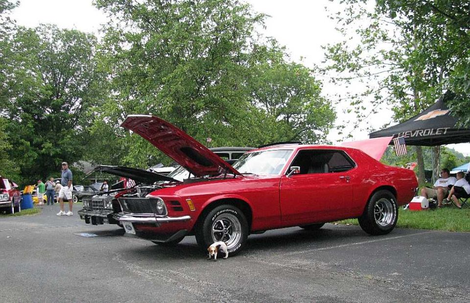 Red classic coupe with hood open, dog in front.