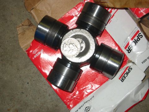 1995 Ford Bronco - A universal joint, also known as a U-joint, is shown with a quarter for scale, resting on Spicer brand packaging.