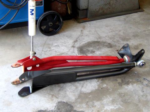 1996 Ford Bronco - Aftermarket suspension control arms and a shock absorber are laid out on a concrete floor.