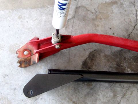 1996 Ford Bronco - Close-up of automotive suspension components, including a shock absorber and control arm, on a concrete surface.
