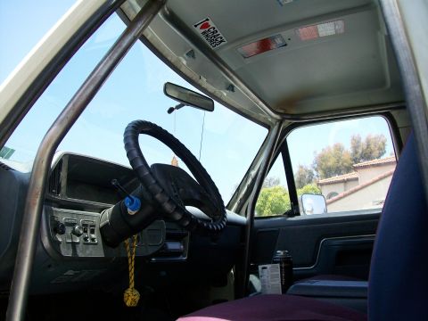 1990 Ford Bronco - Vehicle interior with a prominent roll cage and aftermarket steering wheel visible.