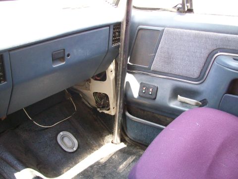1990 Ford Bronco - The interior of a 1990 Ford Bronco, a blue dashboard and door panel, with a purple seat cover visible.