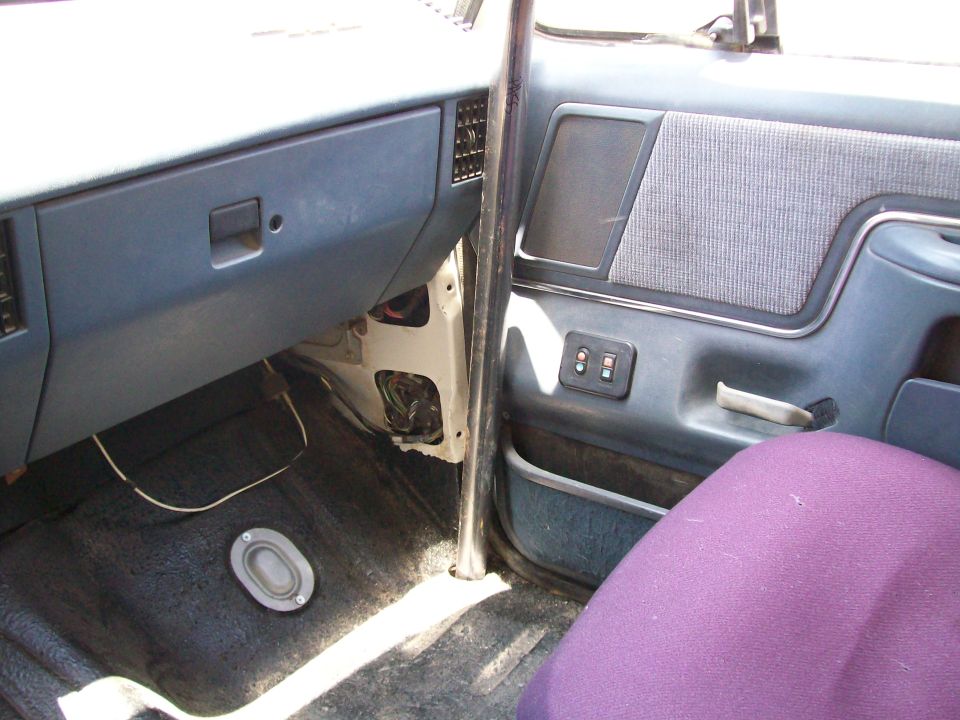 Interior of a 1990 Ford Bronco showing the dashboard, door panel, and a purple seat cover