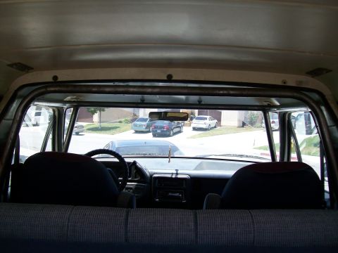1990 Ford Bronco - The interior of a vehicle is shown, a roll cage and a view of the dashboard and the street outside.