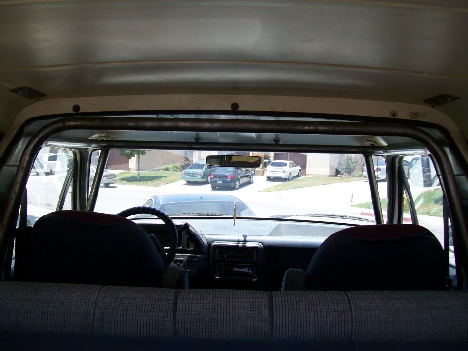 View from back seat of a vehicle, looking forward through a roll cage at the dashboard and out the windshield at other cars