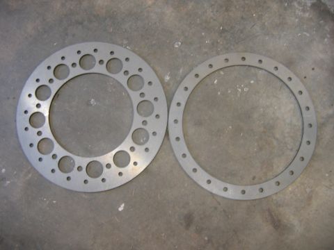 1992 Ford Mustang - Two circular metal parts with multiple holes are shown on a concrete surface.