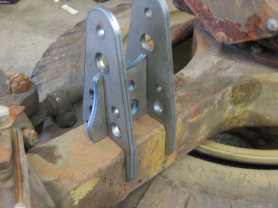 Custom metal brackets welded to a rusty axle housing