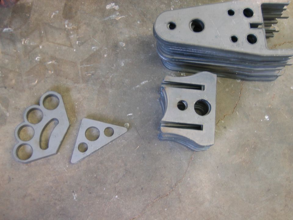 Stack of laser-cut metal brackets on a concrete floor