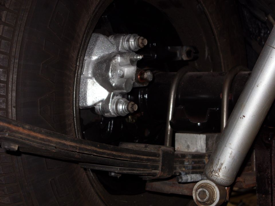 Close-up of a vehicle's rear drum brake assembly with a leaf spring and shock absorber visible
