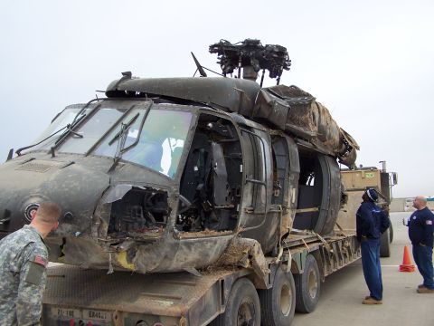 1995 Ford Bronco - A damaged military helicopter is loaded onto a flatbed trailer for transport, with military personnel looking on.