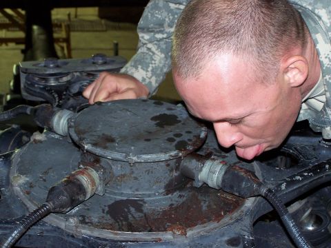 1995 Ford Bronco - Soldier examines a component of what appears to be a military vehicle's drivetrain.
