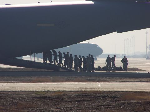 1995 Ford Bronco - Military personnel board a large transport aircraft on an airfield, with another aircraft visible in the background.
