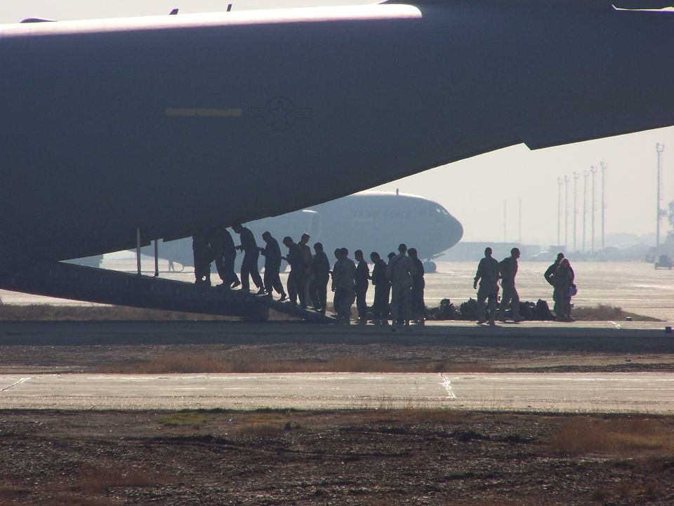 Soldiers boarding large military transport aircraft on tarmac