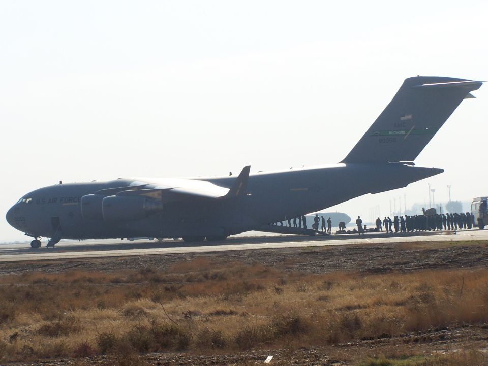 US Air Force cargo plane on tarmac with people gathered nearby