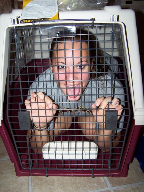 1995 Ford Bronco - Woman playfully poses inside a pet carrier, looking out through the bars.