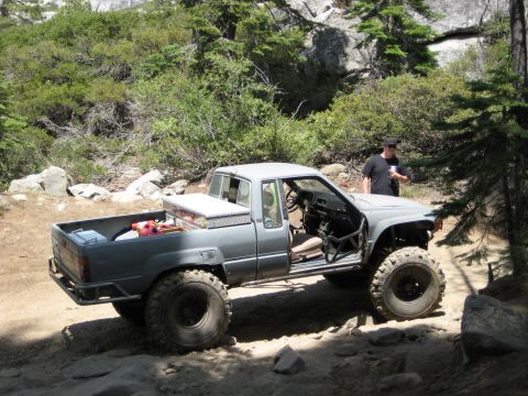 1999 Jeep Grand Cherokee - A modified gray pickup truck sits on a rocky, wooded trail.