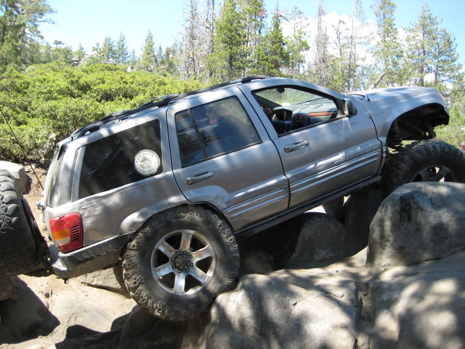 Silver 1999 Jeep Grand Cherokee on rocks, lifted suspension, off-road tires
