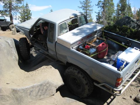 1999 Jeep Grand Cherokee - A modified gray pickup truck tackles a rocky trail with a toolbox and gas can secured in the bed.