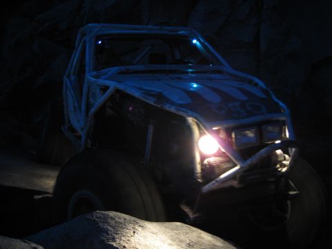 1999 Jeep Grand Cherokee - This heavily modified off-road vehicle navigates a rocky terrain in the dark, illuminated by its headlights.