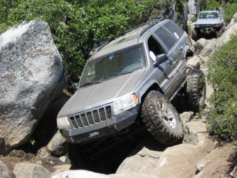 1999 Jeep Grand Cherokee - A 1999 Jeep Grand Cherokee tackles a challenging off-road course with another vehicle following behind.