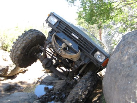 1999 Jeep Grand Cherokee - A Toyota off-road vehicle navigates a rocky terrain, with one wheel lifted high off the ground.