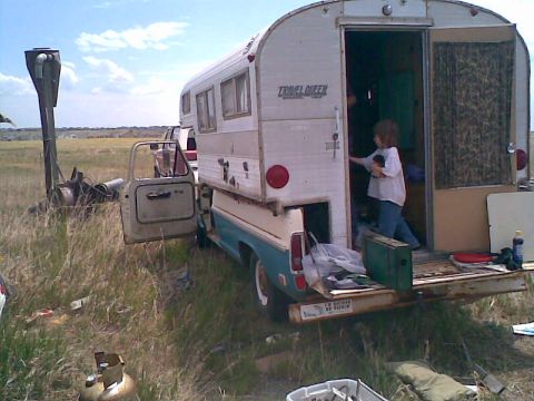 1969 Ford F-100 - A child enters a vintage truck camper parked in a grassy field.