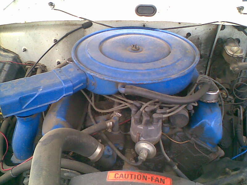 Engine bay with blue air cleaner and distributor cap visible. Caution-Fan sticker on bottom