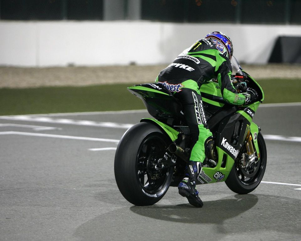 Motorcycle racer in green leathers on a green Kawasaki motorcycle on a track