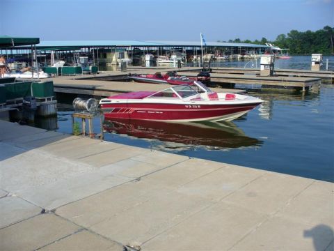 1988 Ford Bronco - A speed boat is docked at a marina on a sunny day, with other boats and covered slips visible.