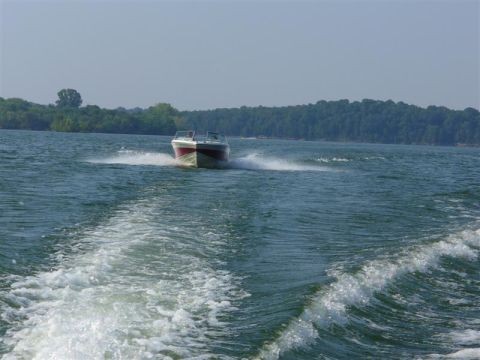 1988 Ford Bronco - A boat speeds across the water, creating a foamy wake behind it under a clear sky.