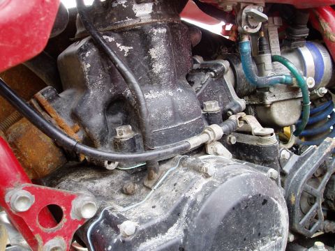 2000 Ford E350 - Close-up view of a dirty motorcycle engine component, showing the cylinder and carburetor.
