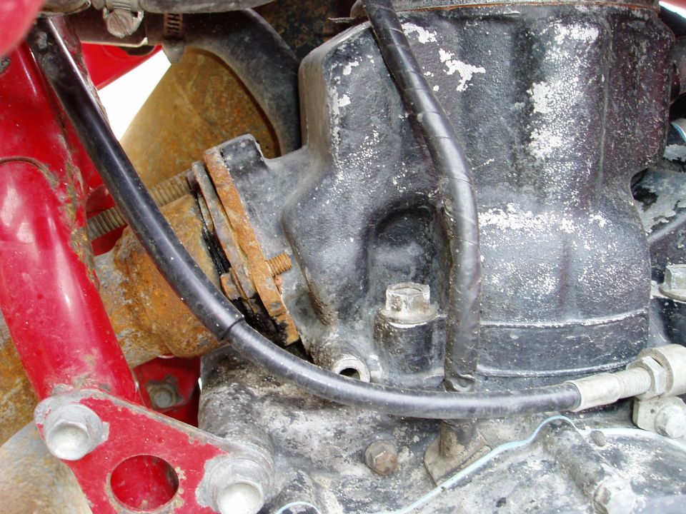 Red frame component attached to a black engine block with rust and white residue