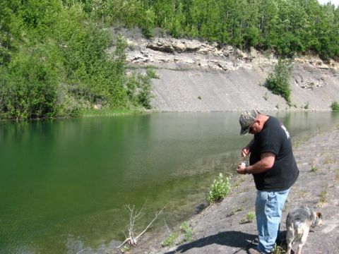 1978 Ford Bronco - A man and his dog stand by a lake with a rocky cliff face in the background.