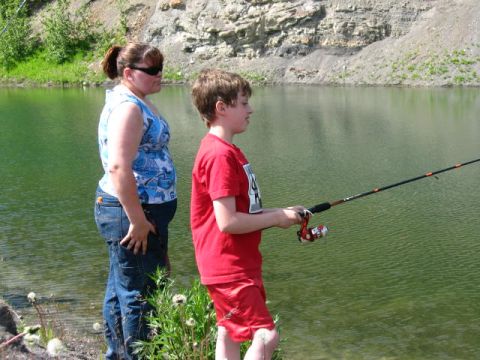 1978 Ford Bronco - A woman and a boy stand by the water's edge, fishing on a sunny day.